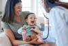 Shot of a baby sitting on her mother's lap while being examined by a doctor